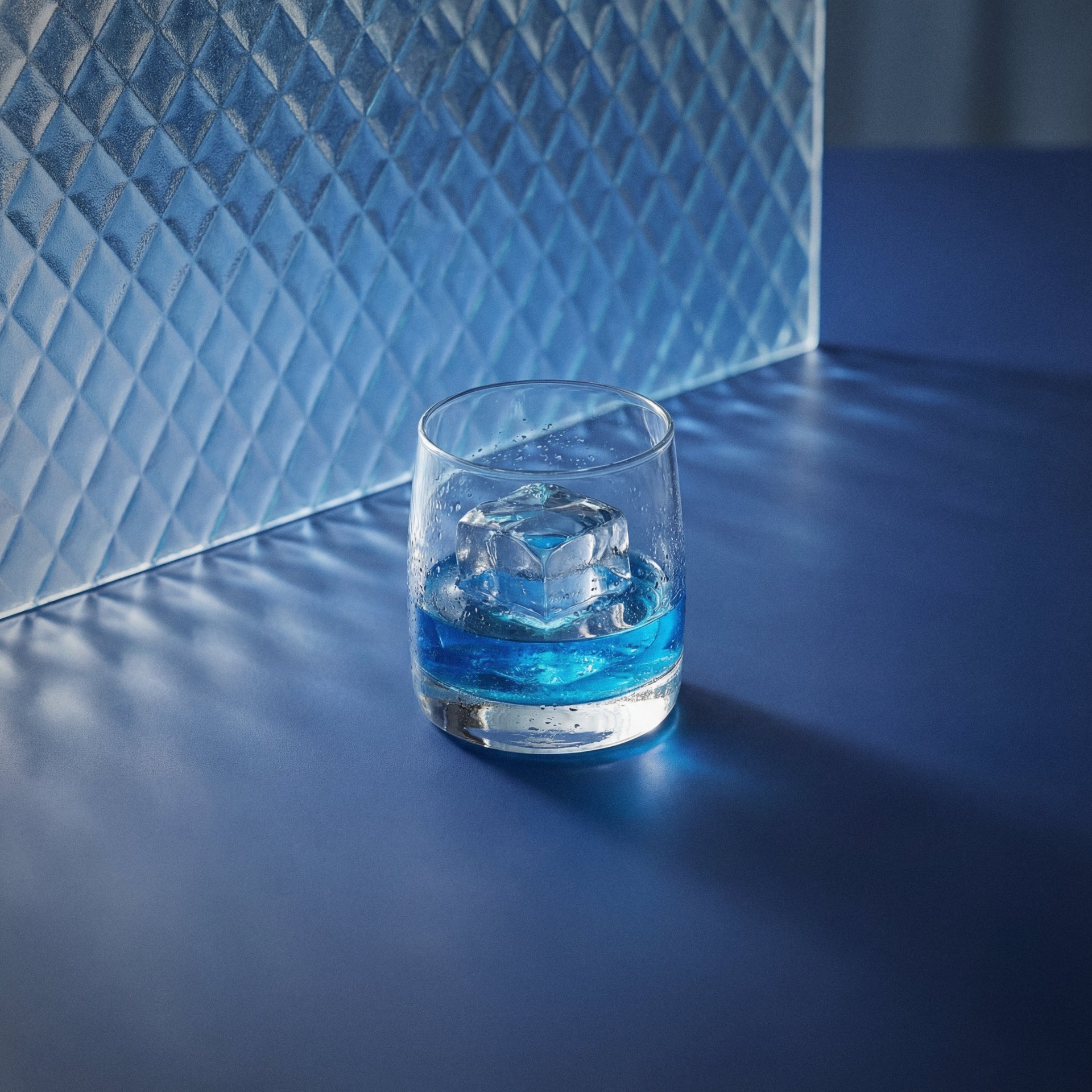 Bols Blue 1575 on the rocks in a rocks glass with ice on a textured surface