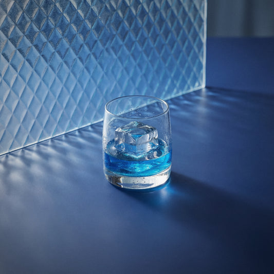 Bols Blue 1575 on the rocks in a rocks glass with ice on a textured surface