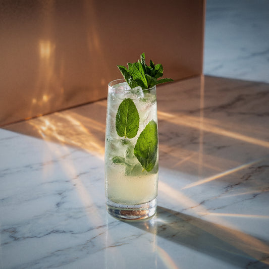 bounty hunter cocktail with coconut liqueur in a highball glass with mint on a textured surface