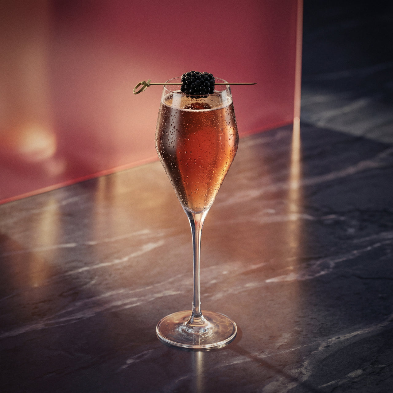 kir royale cocktail made with creme de cassis liqueur in a flute glass and with a blackberry as garnish on a textured background