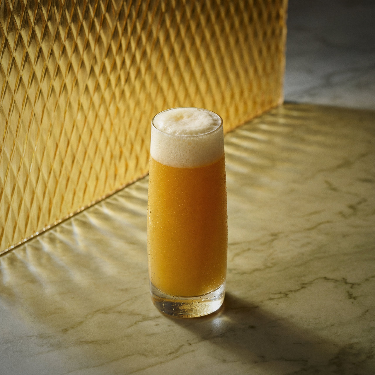 mango michelada cocktail with mango liqueur and with foam on a textured surface