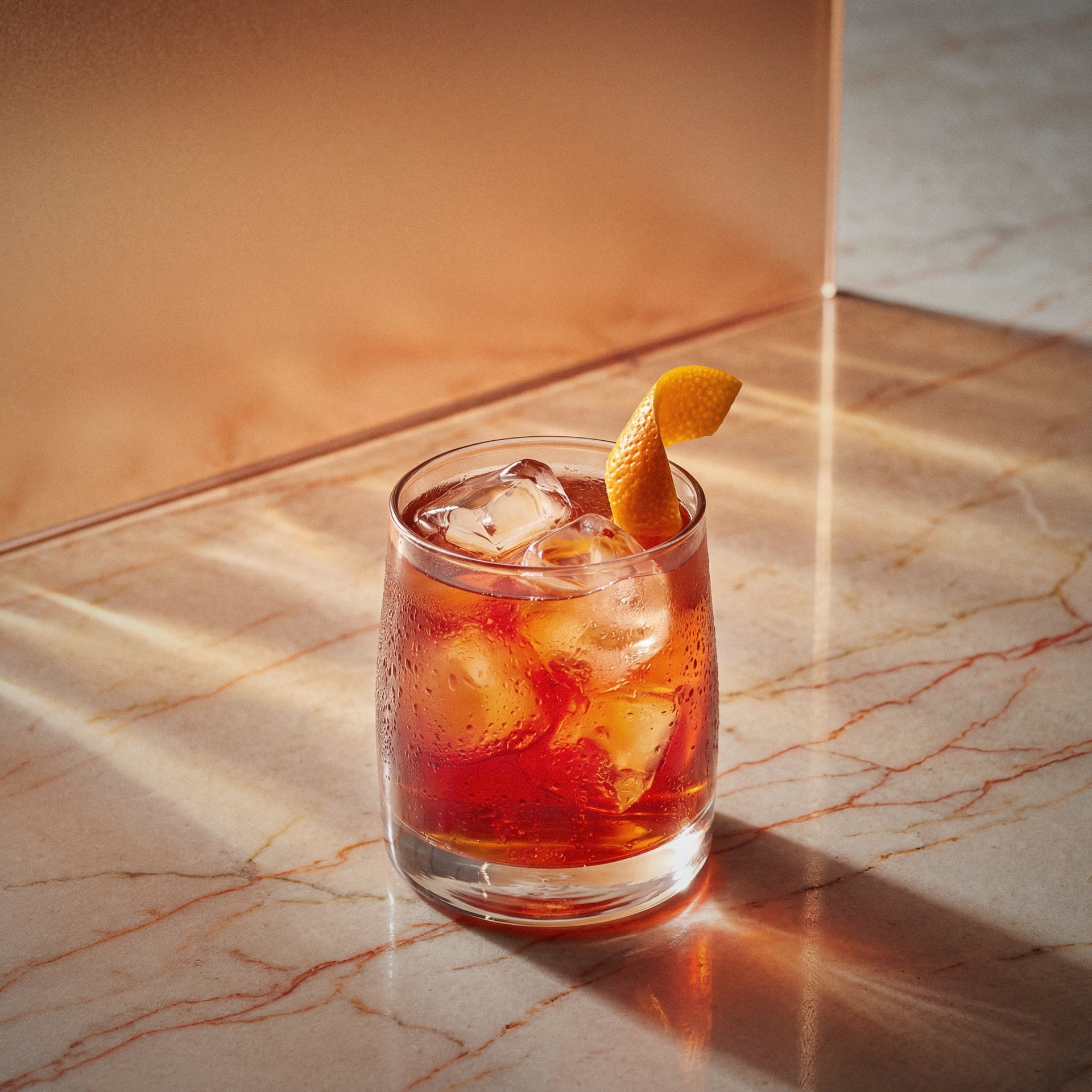 Very old fashioned cocktail with barrel aged genever in a rocks glass with an orange twist on a marble surface