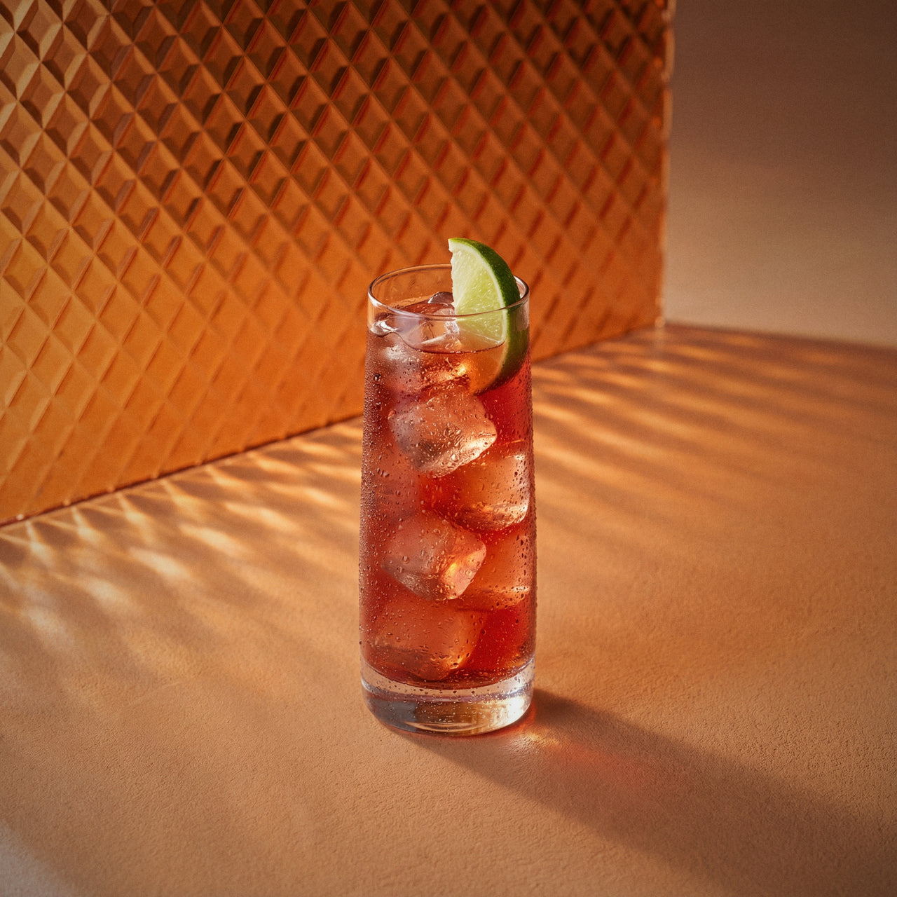 woo woo cocktail with peach liqueur and vodka in a highball glass with lime wedge on a textured surface