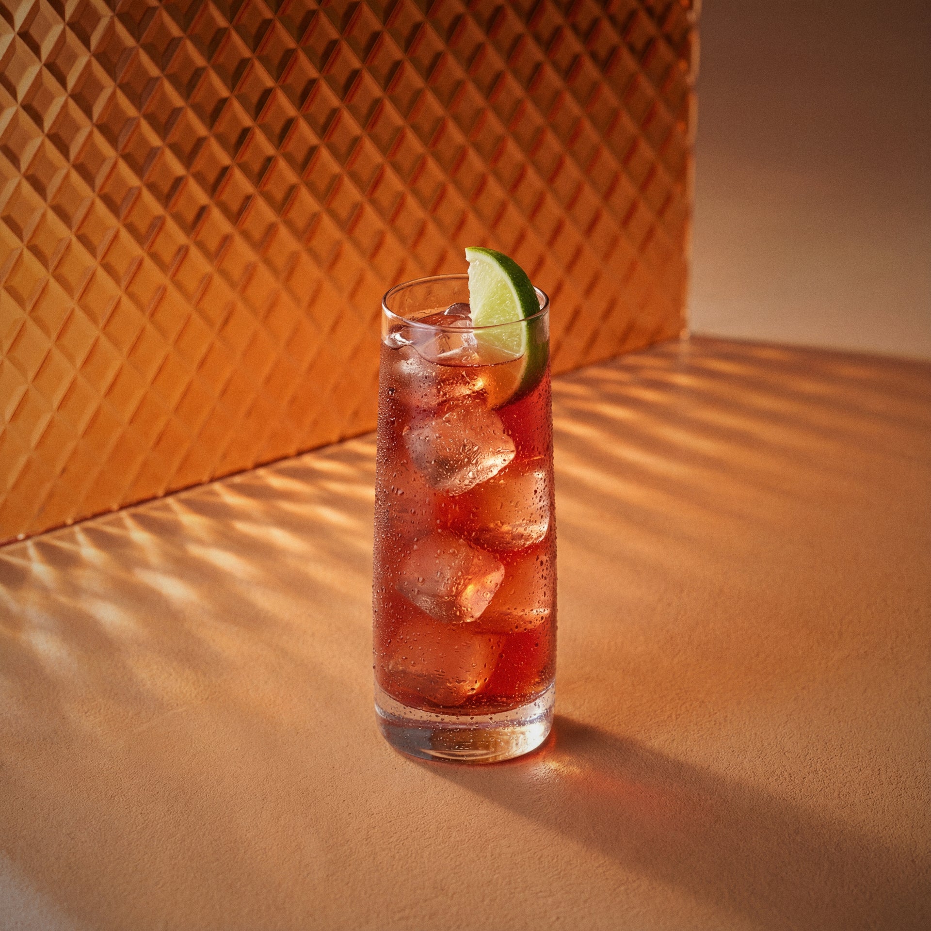 woo woo cocktail with peach liqueur and vodka in a highball glass with lime wedge on a textured surface